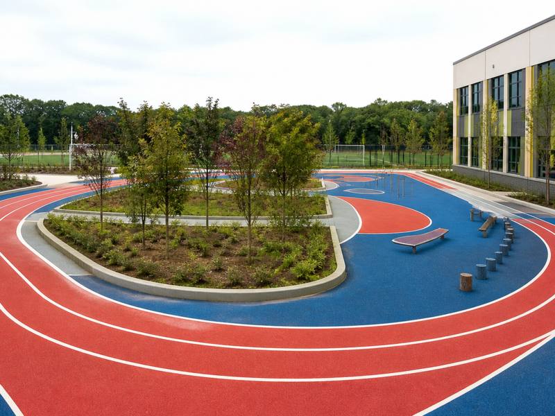 Red and blue rubber running track laid around a school field by Oshawa Rubber Surfacing.